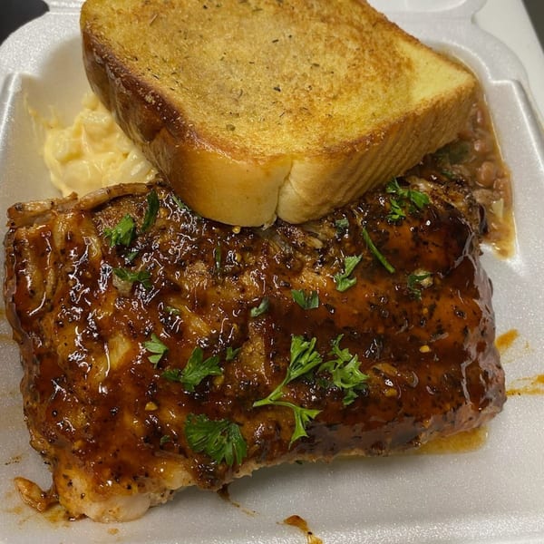 Southern-style BBQ ribs with mac and cheese, baked beans, and Texas toast in a takeout container.